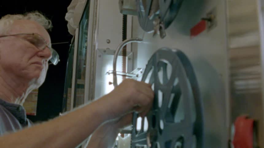 Older man thread film onto real on projection machine