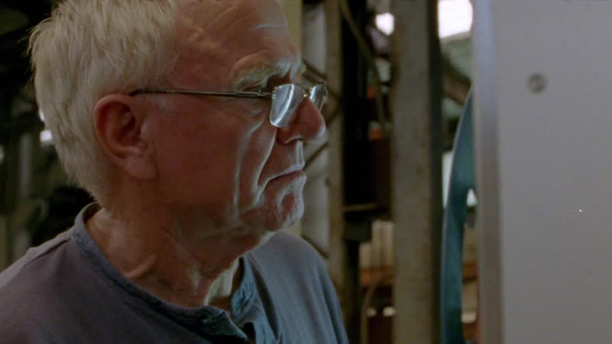 A man is looking at a film reel machine