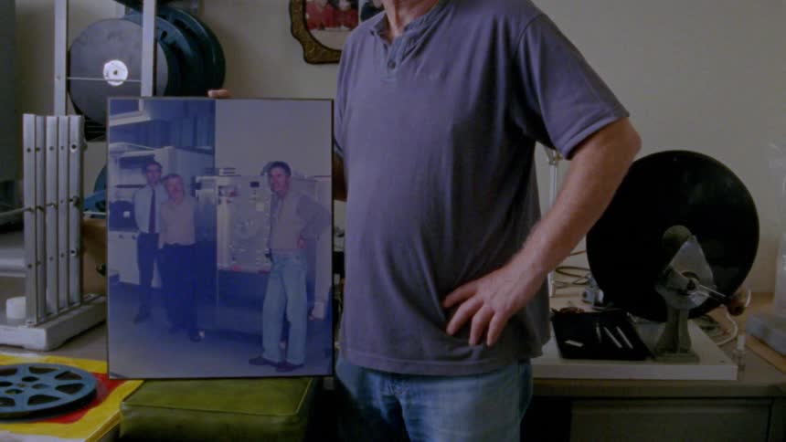 A man holds a large portrait of people posing in photo