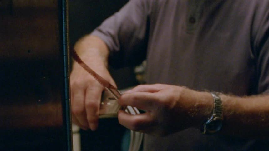 Older man with white hair staples film strips together