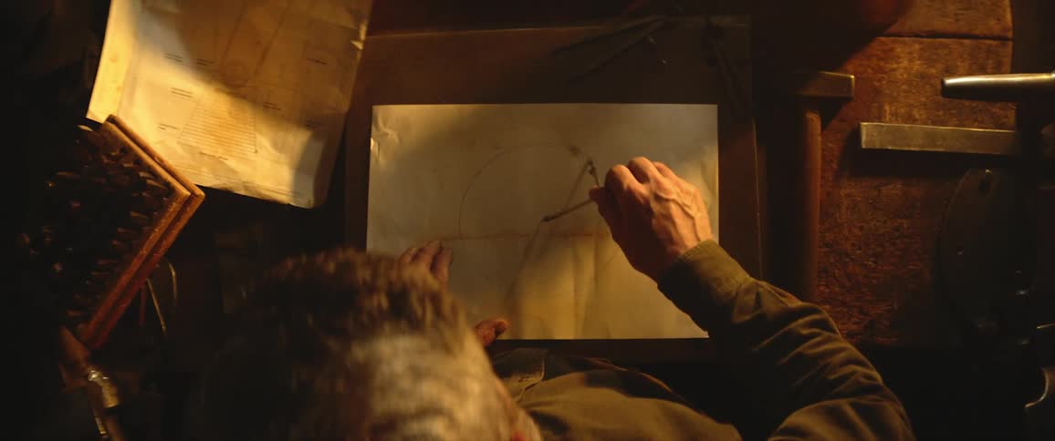A person in a room using a compass to make a circle on a paper on a table