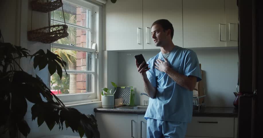 A doctor is talking on his phone by the window