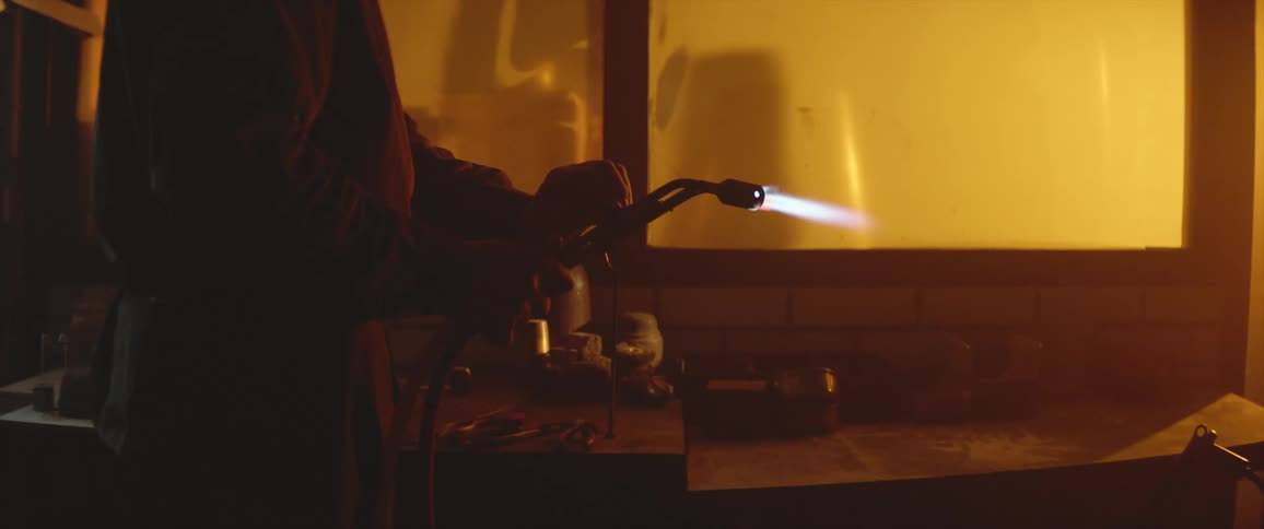 Man working on a workshop lights up a torch