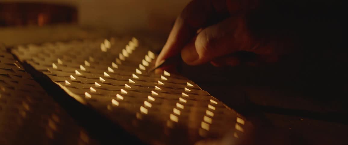 Person uses hand tool to on pattern grooves on metal sheets