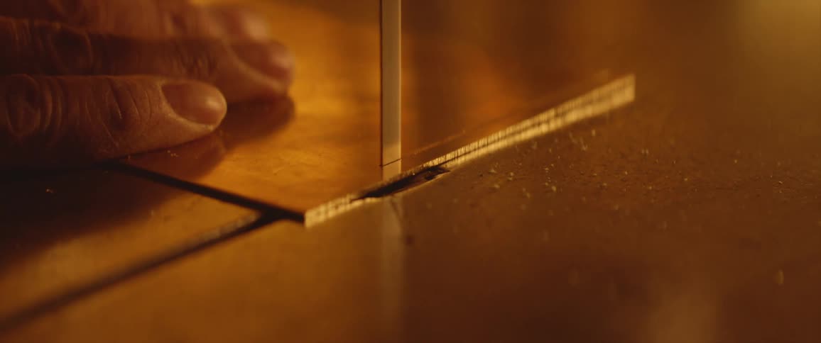 A person in a room cutting a piece of leather with a power saw