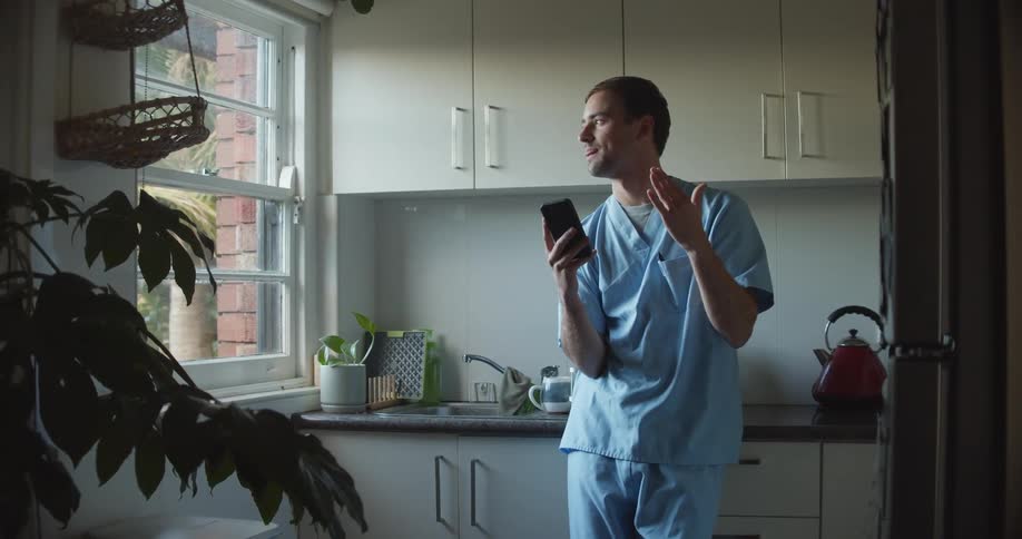 A man stands in a small kitchen talking on a cell phone