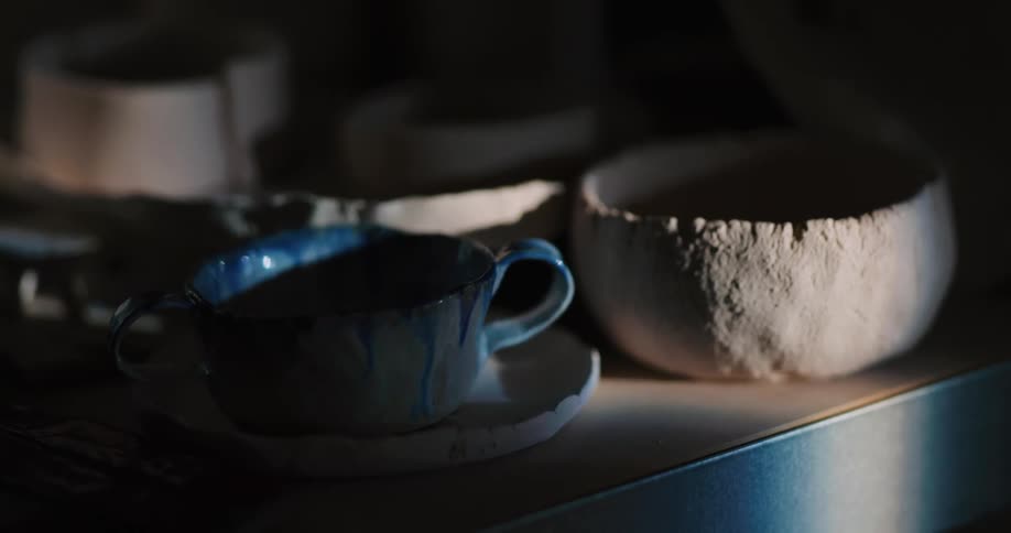 Handmade bowls and a cup and saucer sit on a small table