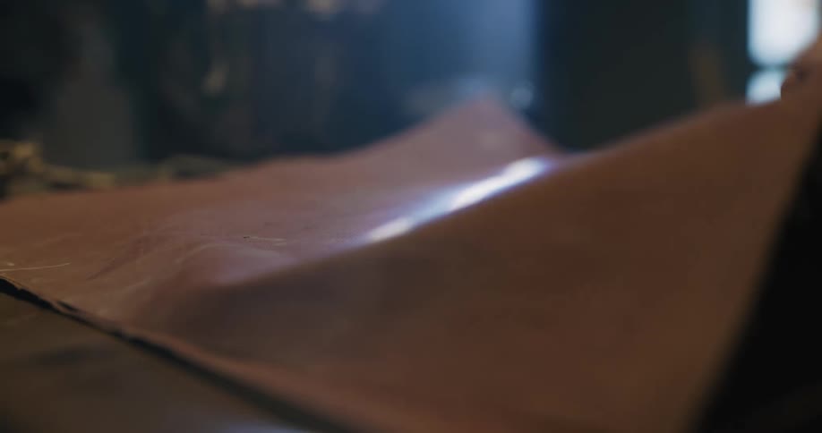 A person that is working on a piece of leather in a room