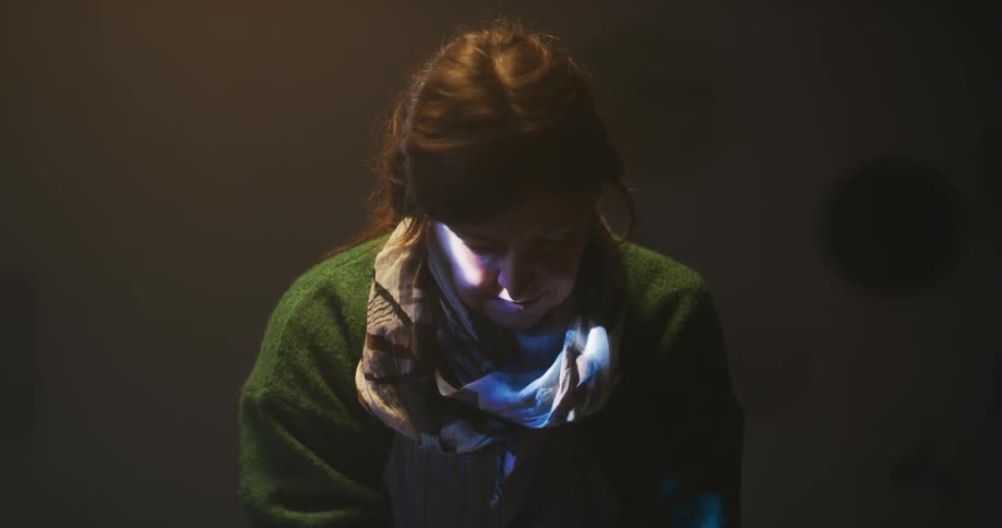 A woman pushes down on a table as a light beam flashes across her face