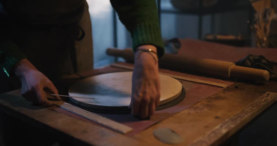 Woman cutting clay for pottery using a wooden mold in the workshop
