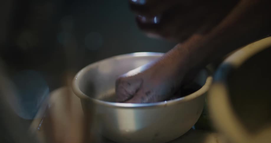 Person washing hands on a small bowl inside a dimly lit room