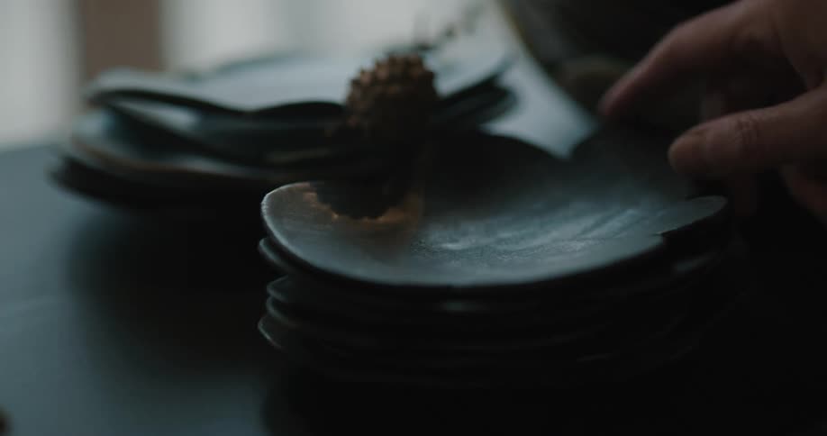 Person select artistically shaped shallow clay bowls from a stack