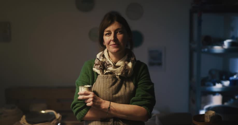 A woman is in the kitchen drinking from a cup