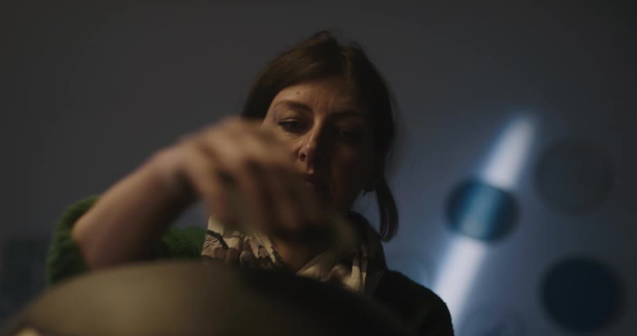 Woman scrapping the surface of a clay sculpture inside a dimly lit room