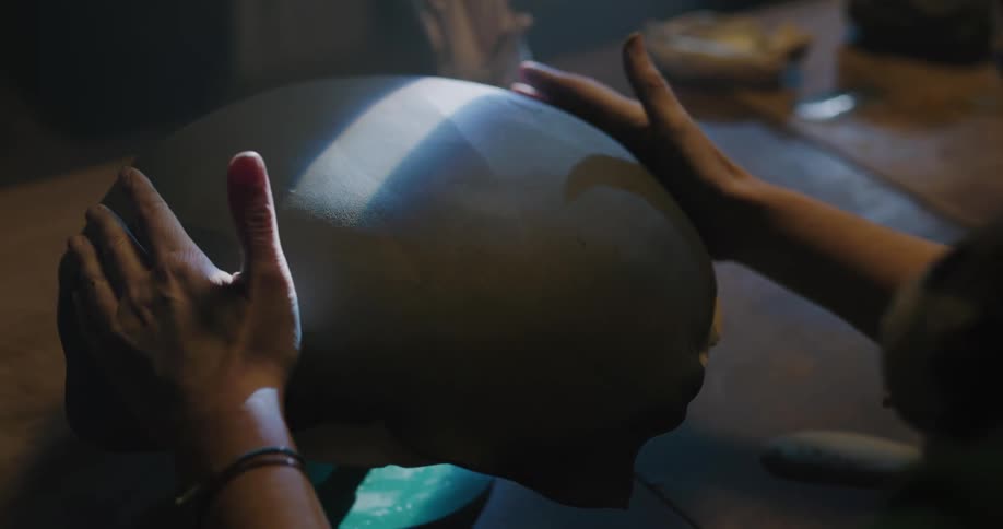 A person in a room shaping a piece of clay
