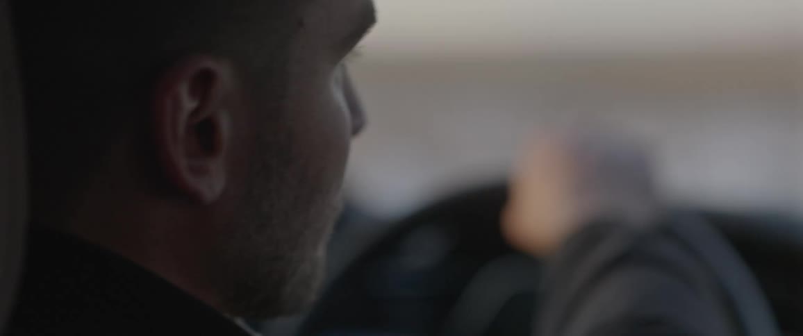 A man driving turns and nods with satisfaction
