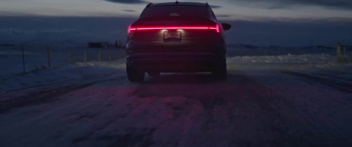 A car drives down a snowy road in a rural area