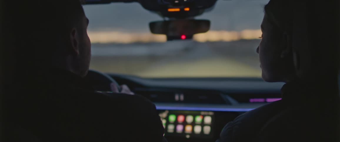 A man and a woman in a vehicle with the sky and clouds in the background