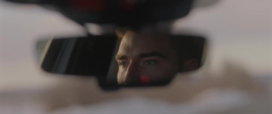 Man driving a car on the countryside reflected on the rearview mirror