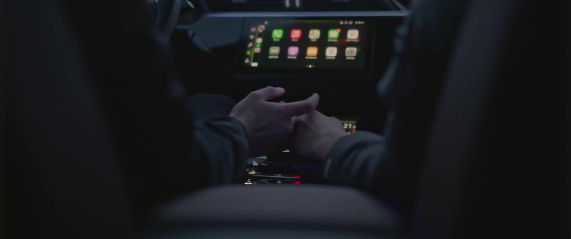 A boyfriend and girlfriend holding hands while driving