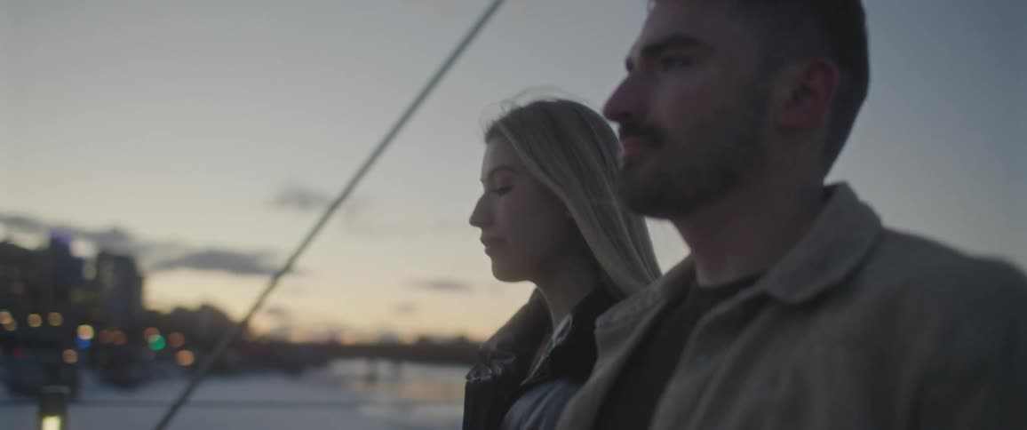A man and woman walk across a bridge towards the city skyline