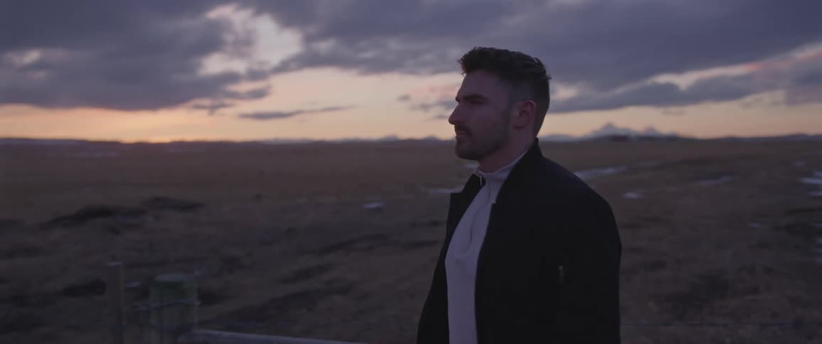 Young man standing on a road in the countryside at evening