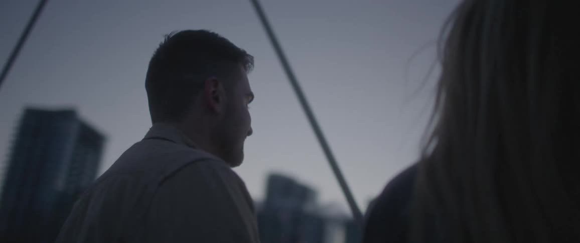 A man looks at his date as they stand near tall skyscrapers