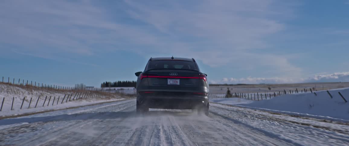 Black car driving on a snow covered road in the countryside at morning