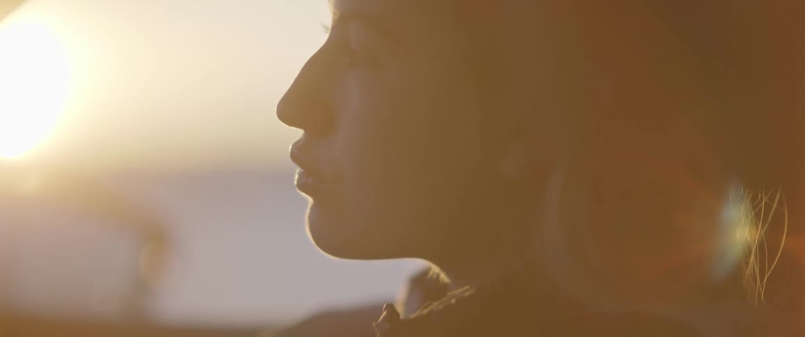 Blonde female passenger leans head on hands partly silhouetted by sun