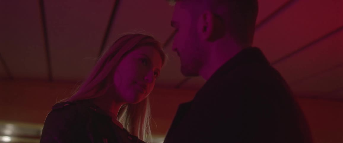 A man and woman looking at each other passionately in a dark room