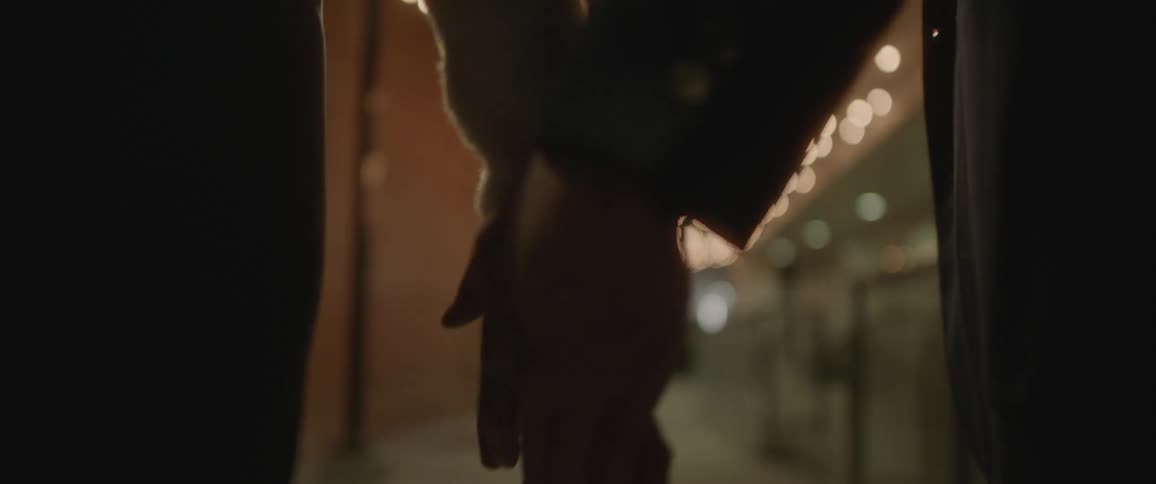 Young couple holding hands while walking under the night lights on a city street