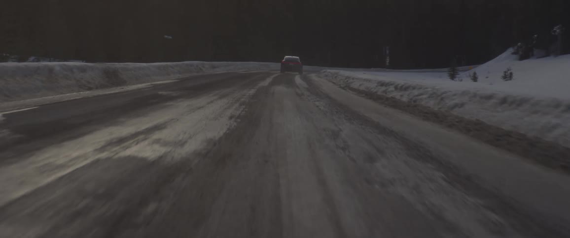 Dark grey audi car drives on snowy dirt road in the forest