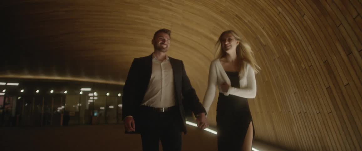 A man and a woman holding hands and walking in a tunnel