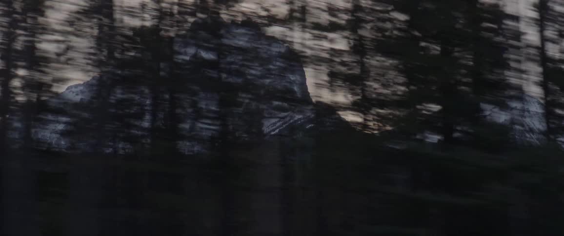 A mountain stands tall and is covered in snow as the camera passes by quickly