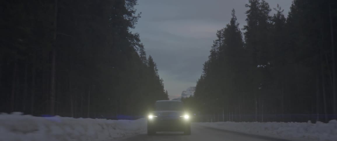 Black sports car with headlights on driving on a rural road in the countryside at night