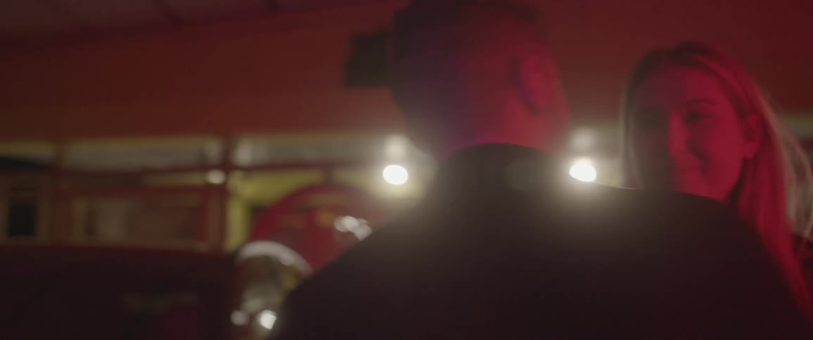 Man with a beard and blonde woman kiss each other next to audi car at night