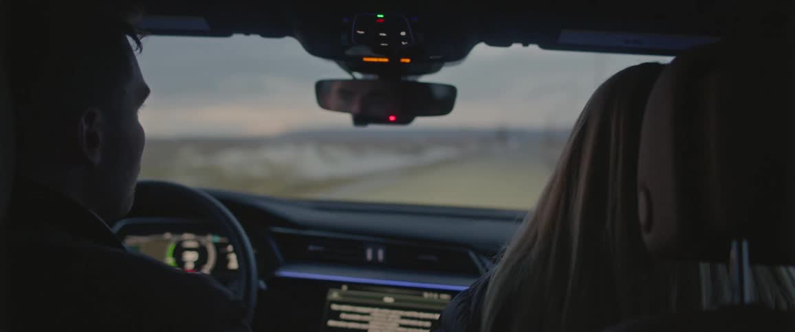 Young couple on a road trip driving a car on a rural road at morning