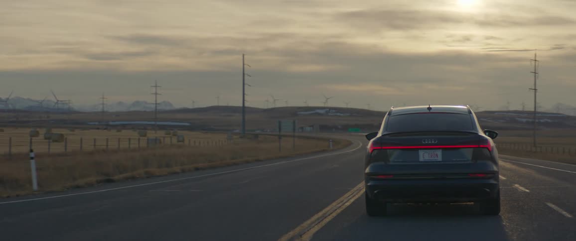 A car is driving past the windmills