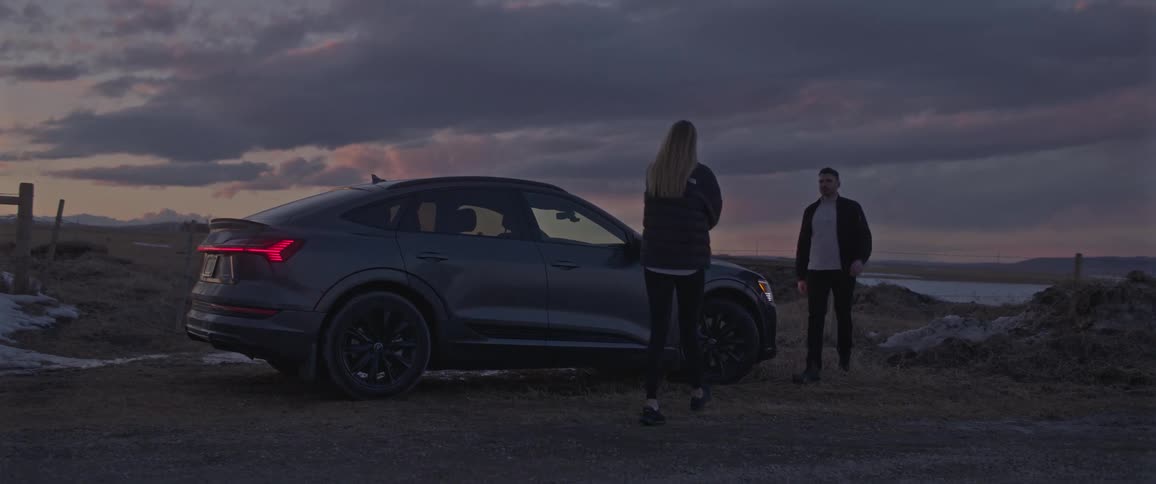 Young couple walking and talking around a car parked on the countryside at morning