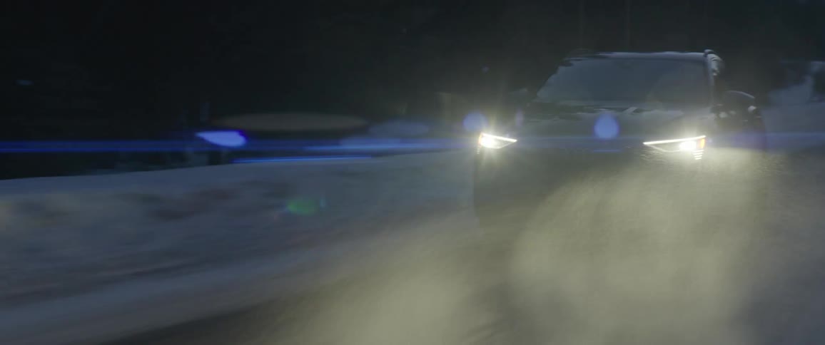 A vehicle kicks up snow dust driving on a rural road