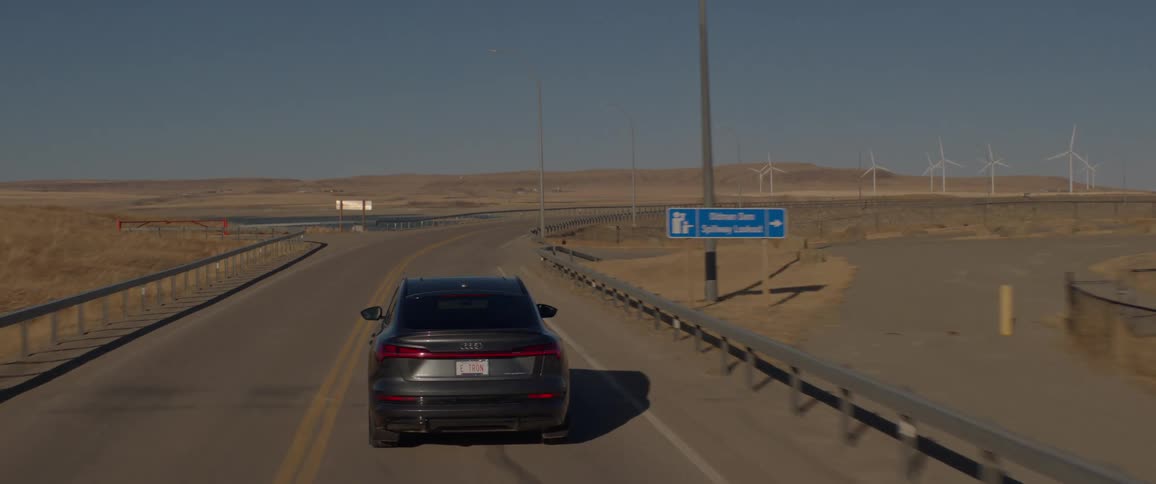Black car driving on a road through the countryside at daytime