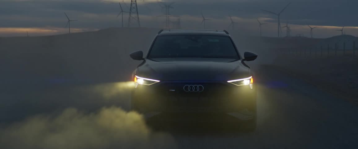 A vehicle driving on a road with wind turbines the sky and clouds in the background