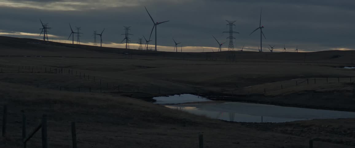A wind farm of spinning turbines and utility towers