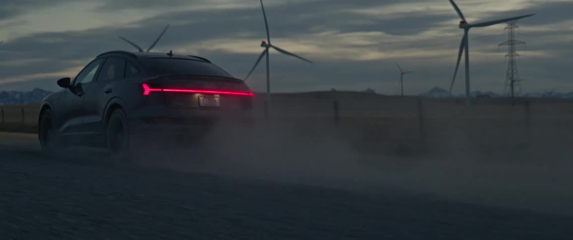 A car drives on a straight road with multiple windmills at a distance