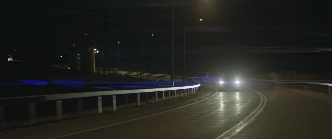 A vehicle travels a highway at night