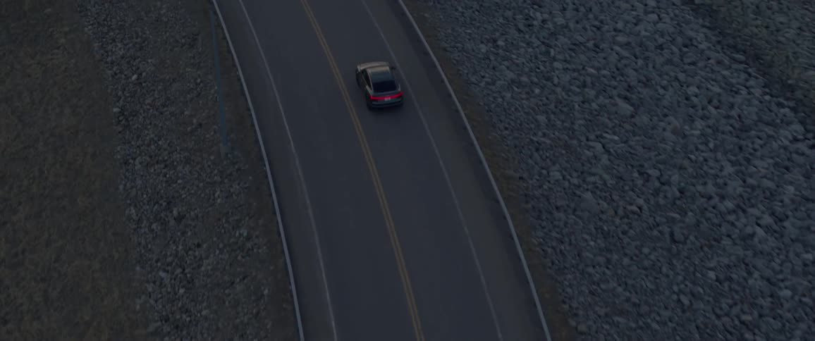 Black car driving on a road on the counryside in the morning