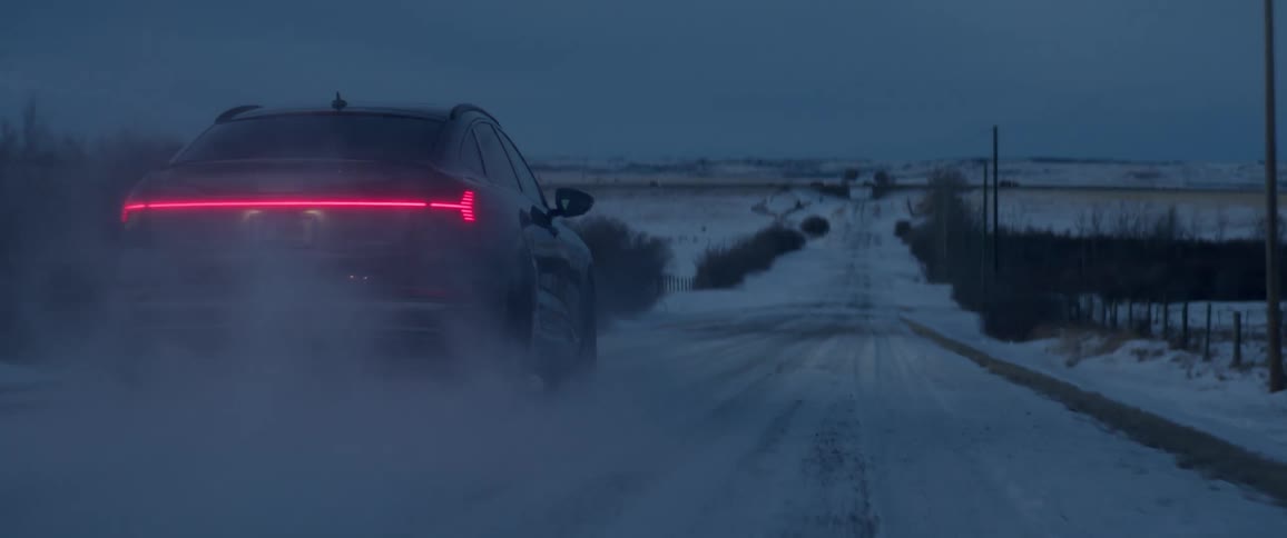Black car driving on a snow covered road in the countryside at morning