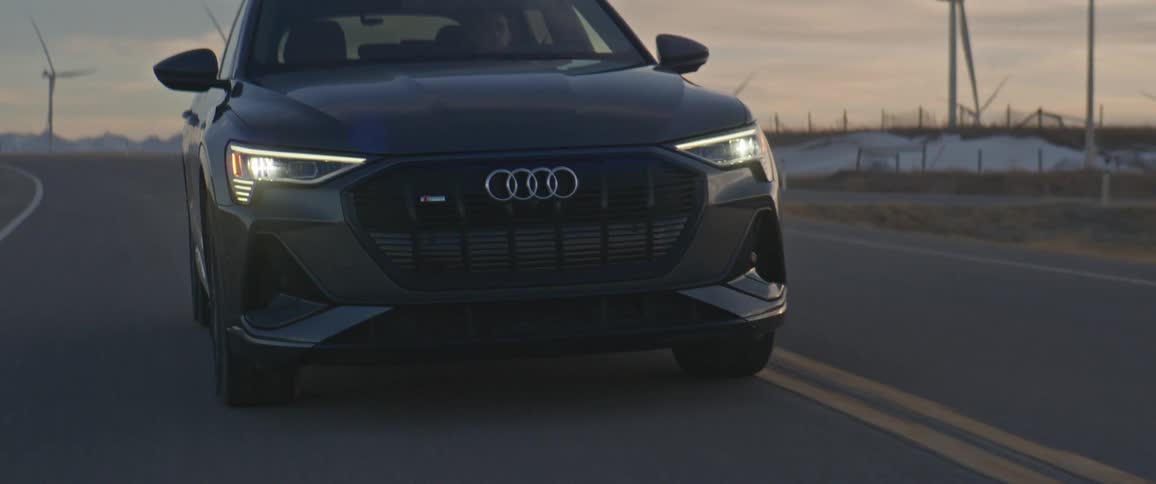 A car is driving on a rural highway at dusk