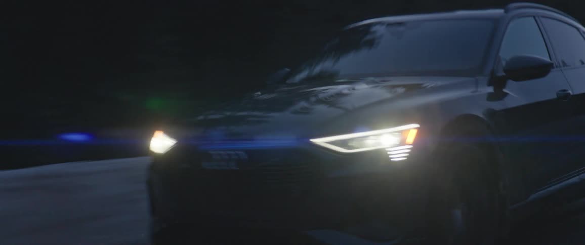 A car travels down a rural road on a wintry evening