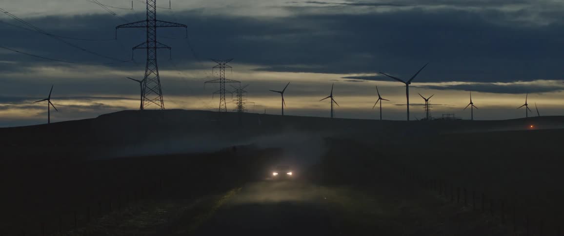 A car is driving in a rural area at dusk